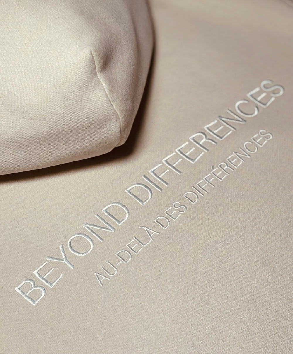 Gros plan de la broderie ton sur ton BEYOND DIFFERENCES du Heavyweight Hoodie Beige Allié
