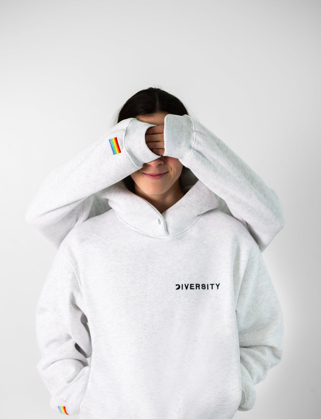 Deux personnes en hoodies Diversity gris, le visage caché par leurs mains