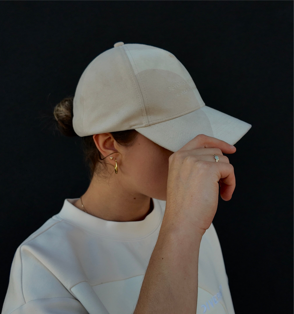 Personne portant la casquette beige en suède végane, main sur la visière