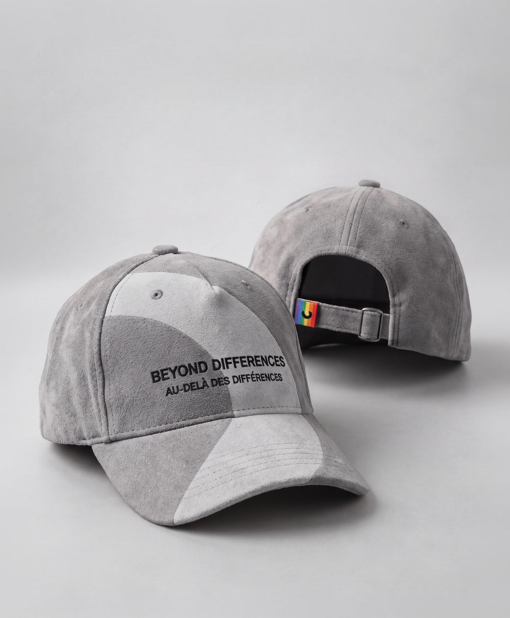 Deux casquettes en suède végane grises, broderie noire BEYOND DIFFERENCES et étiquette arc-en-ciel à l'arrière