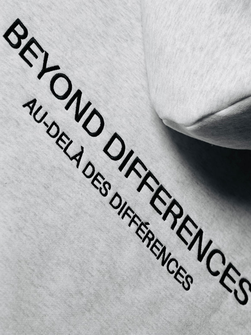 Gros plan de la broderie BEYOND DIFFERENCES / AU-DELÀ DES DIFFÉRENCES du Heavyweight Hoodie Gris