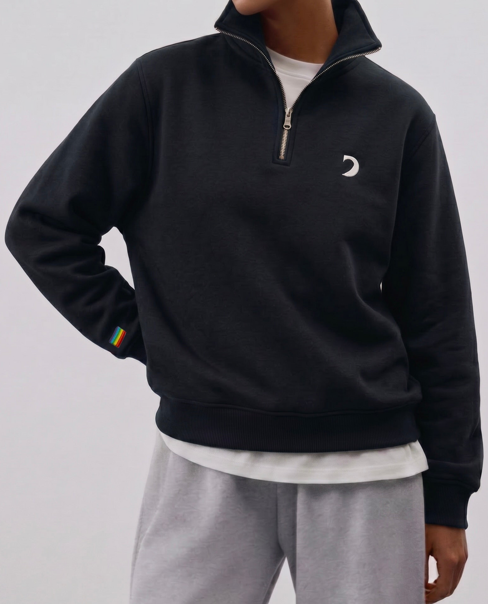 Chandail 1/4 zip noir porté avec un pantalon gris
