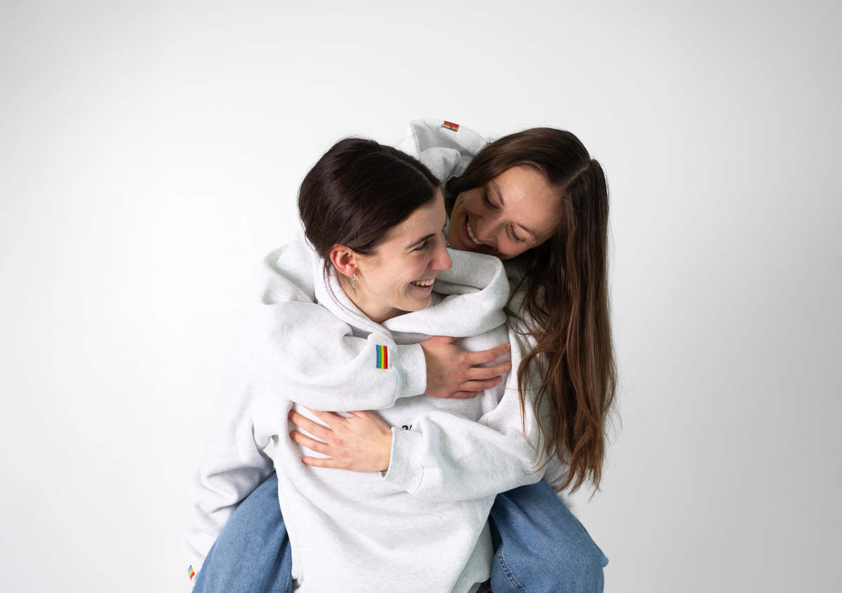 Deux personnes enlacées en hoodies gris Diversity sur fond blanc