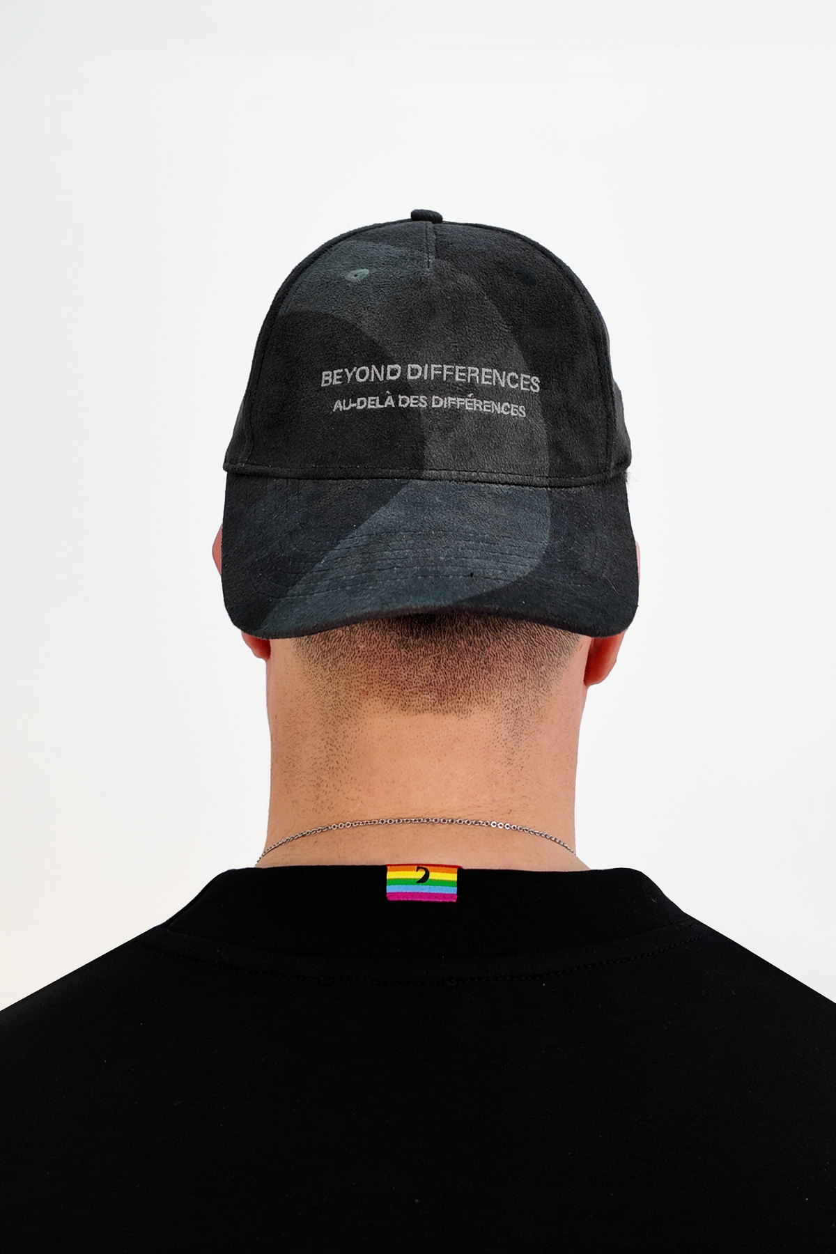 Person seen from behind wearing the black vegan suede cap backwards, BEYOND DIFFERENCES embroidery visible