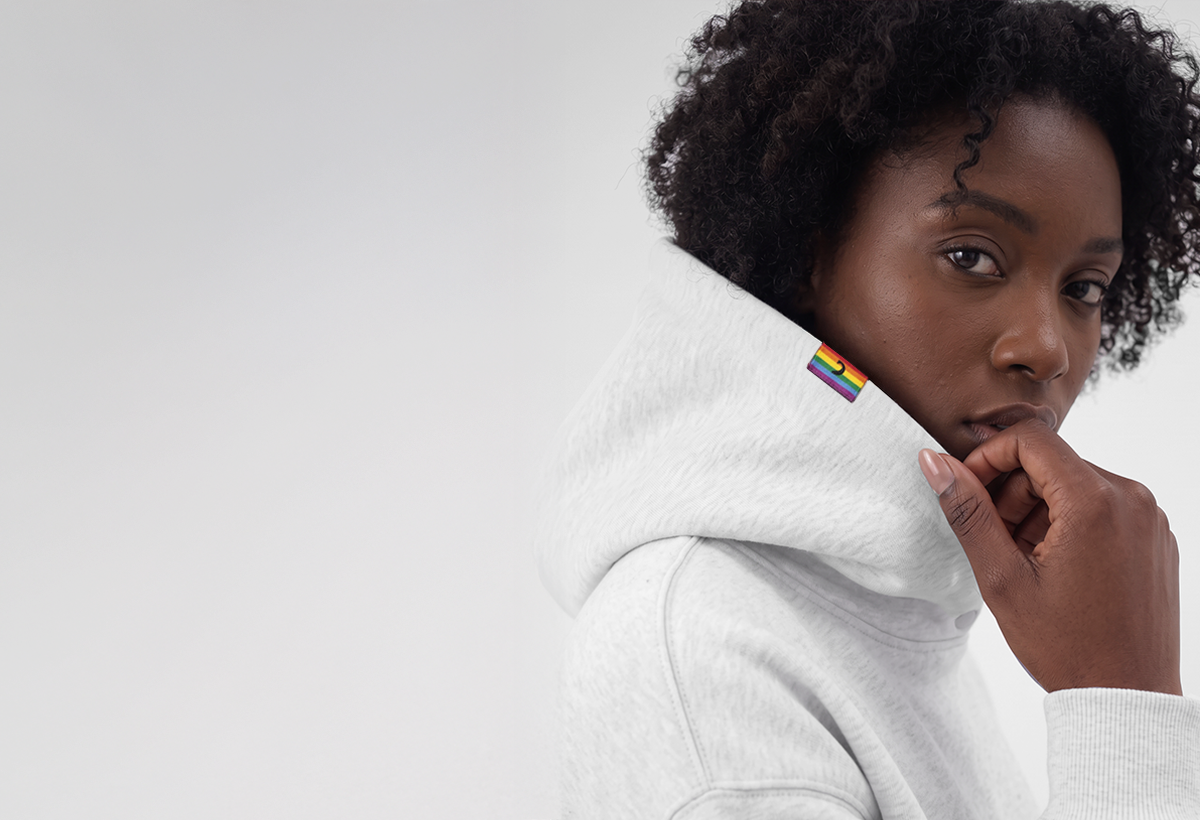 Person wearing a grey Diversity hoodie, rainbow flag tag on the hood