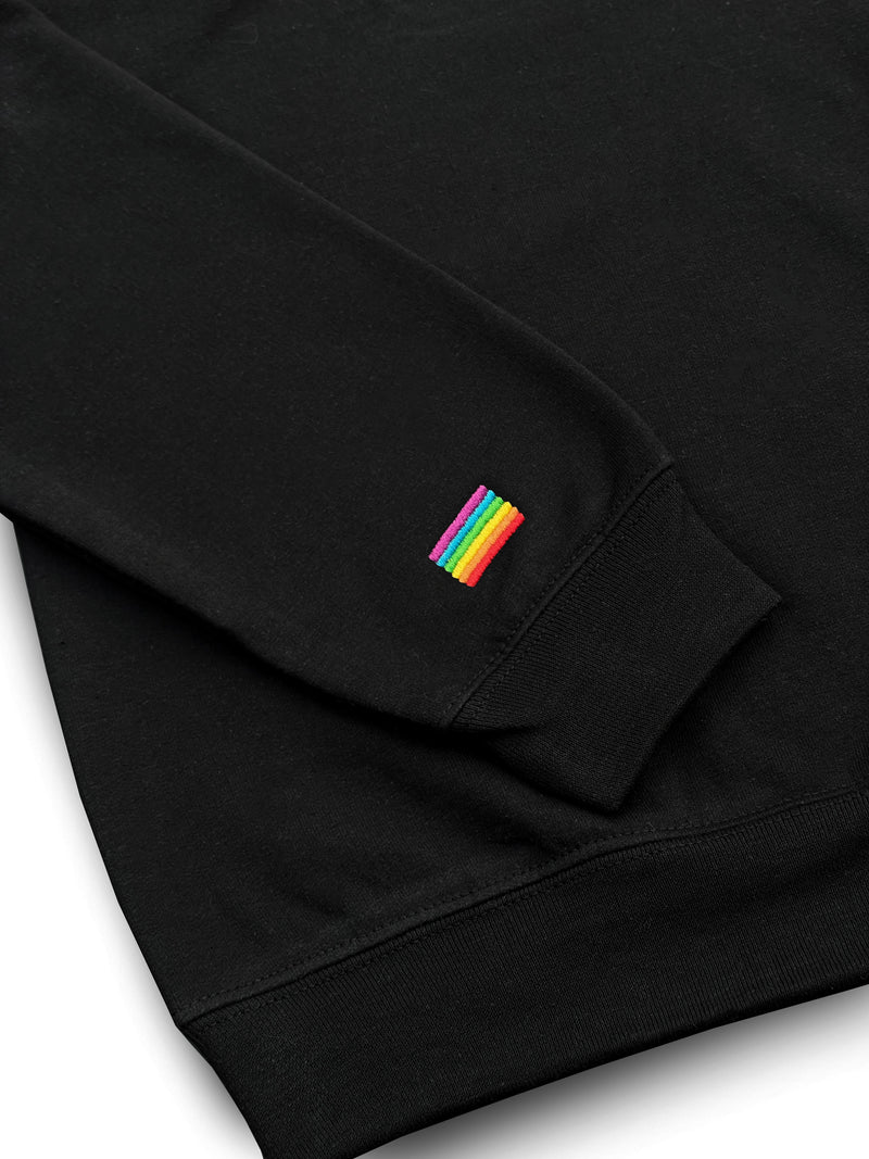 Close-up of the rainbow flag embroidered at the cuff of the black quarter-zip