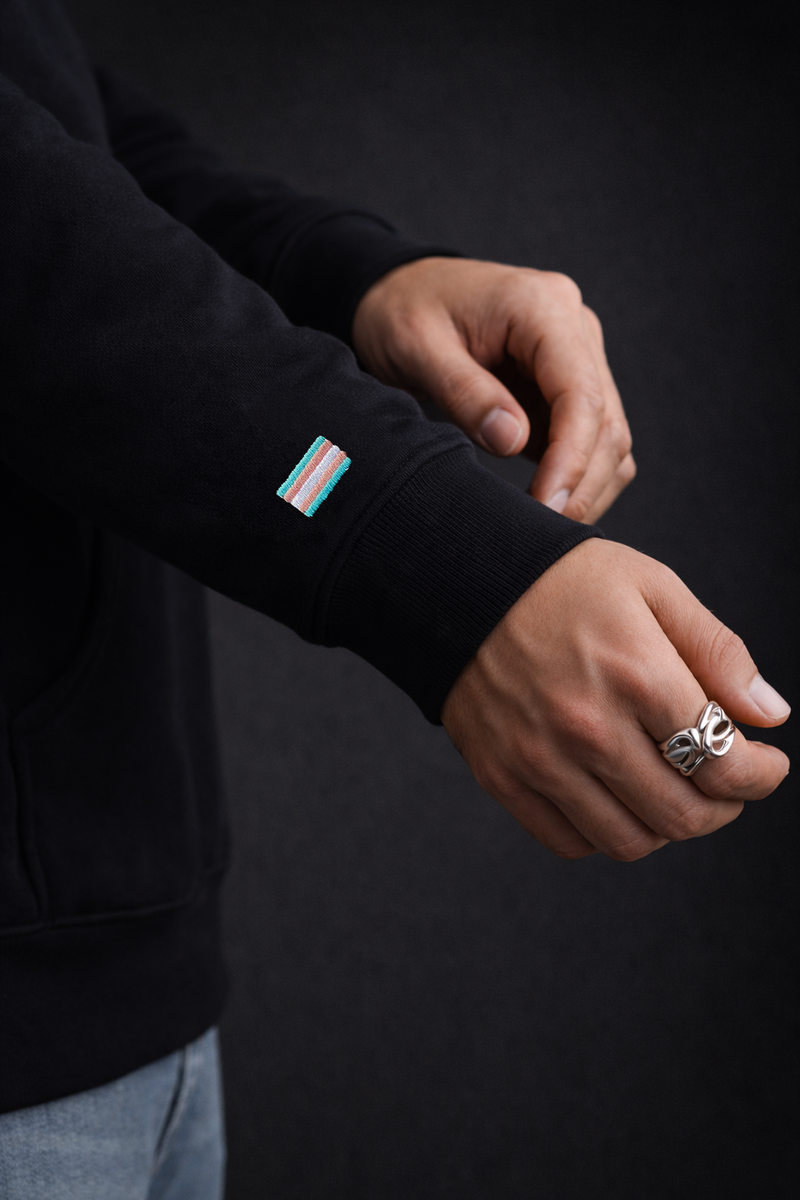 Trans flag option embroidered on the sleeve of a black midweight piece