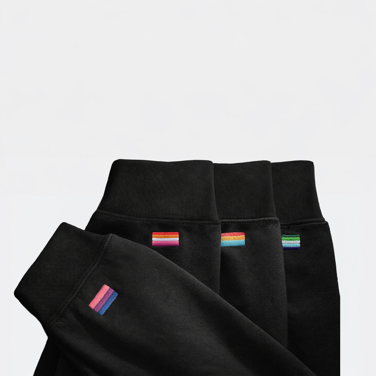 Sleeves of black midweight pieces with different embroidered pride flags