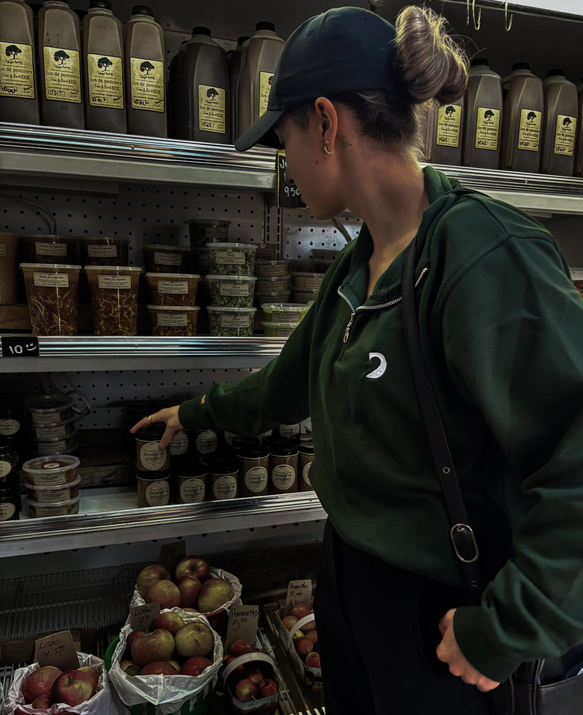 Personne portant le chandail 1/4 zip vert forêt et une casquette noire à l'épicerie