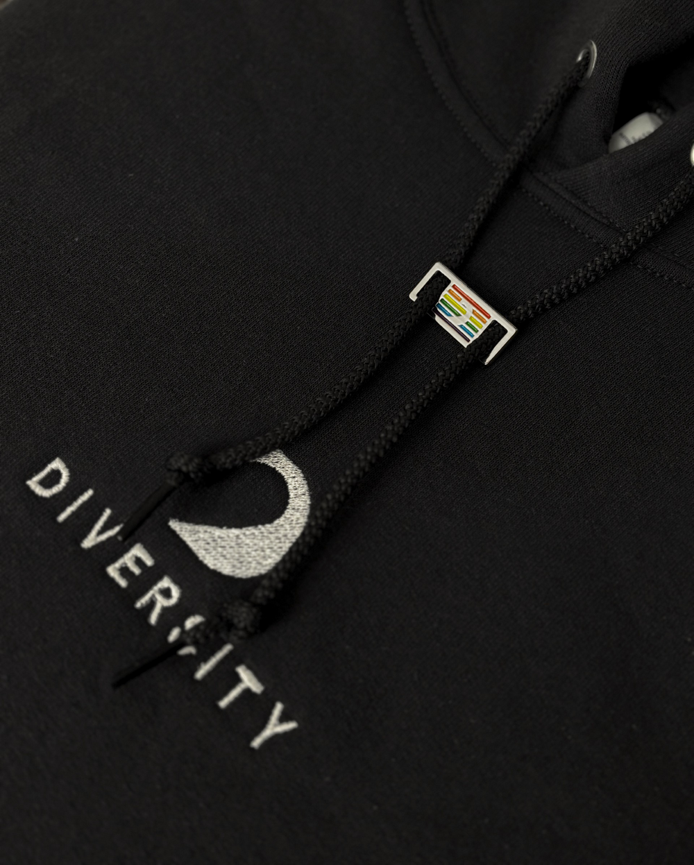Pin D'Lux arc-en-ciel sur le cordon d'un hoodie noir Diversity