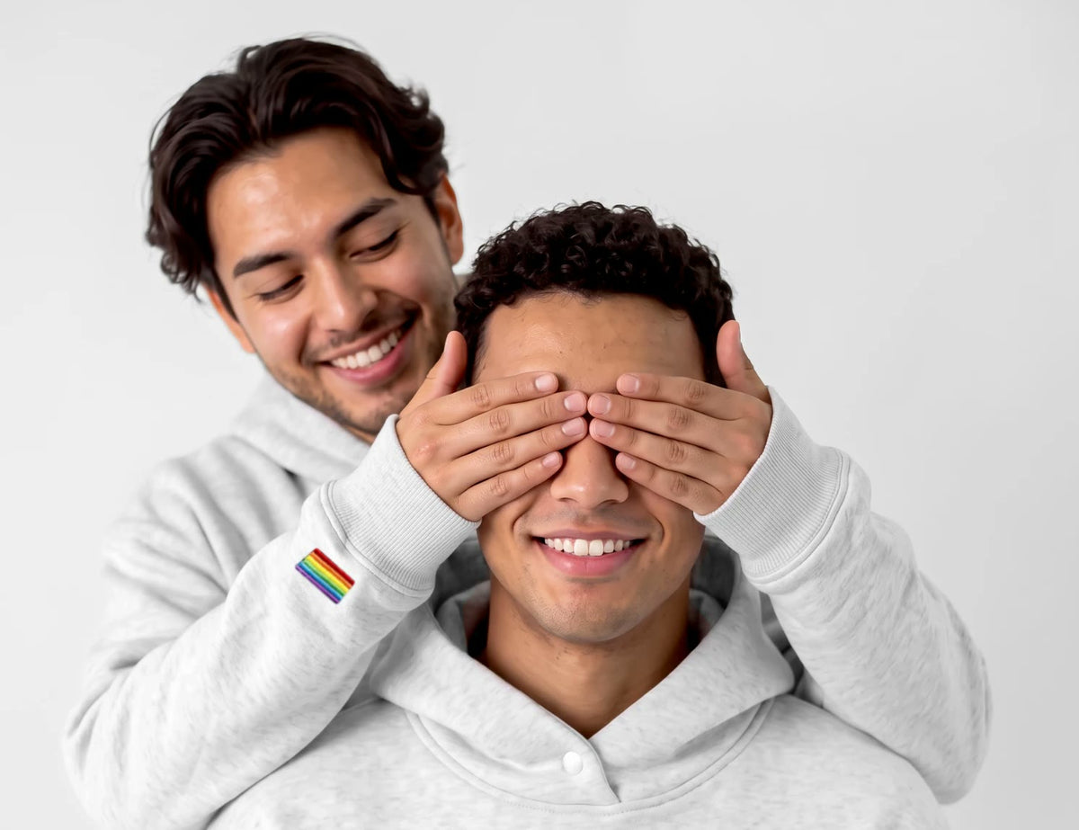 Deux personnes en hoodie gris : l'une cache les yeux de l'autre, qui sourit